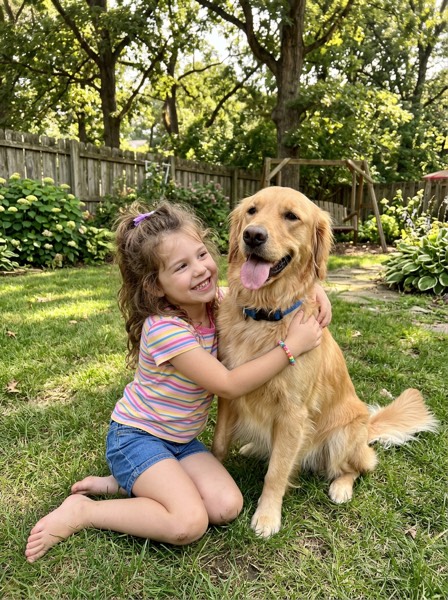 Photo of a girl hugging her golden retriever